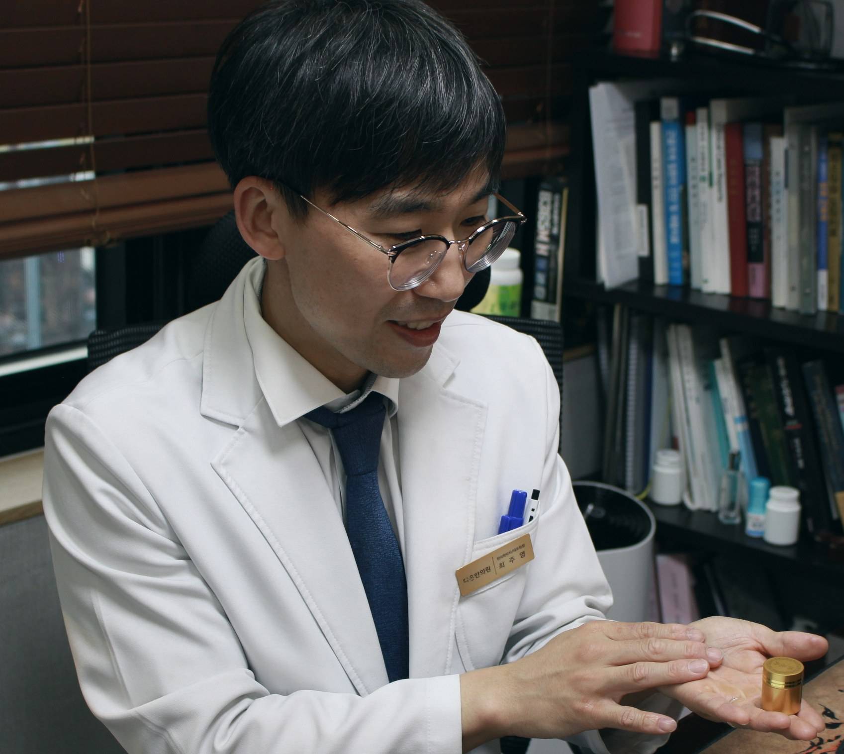 다온한의원 최주영 대표원장이 진료실에서 손바닥에 금색 케이스를 올려 두고 설명하는 모습