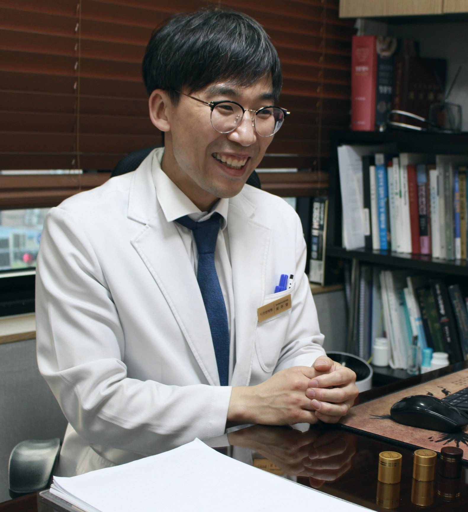 다온한의원 최주영 대표원장이 진료실 책상 앞에서 웃으며 이야기를 듣는 모습